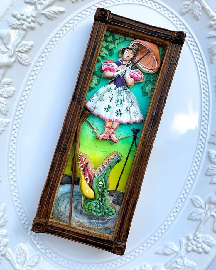 3-D cookie of the Haunted Mansion's Stretching Room Portrait with a woman on a rickety tightrope and an alligator below her