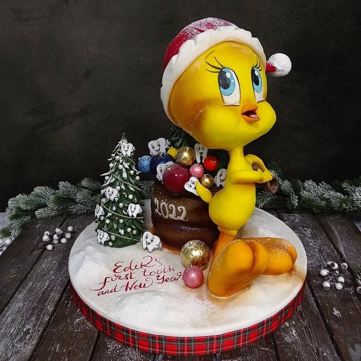 This Tweety Bird Christmas Cake features Tweety wearing a Santa hat and carry a bag filled with Christmas presents.