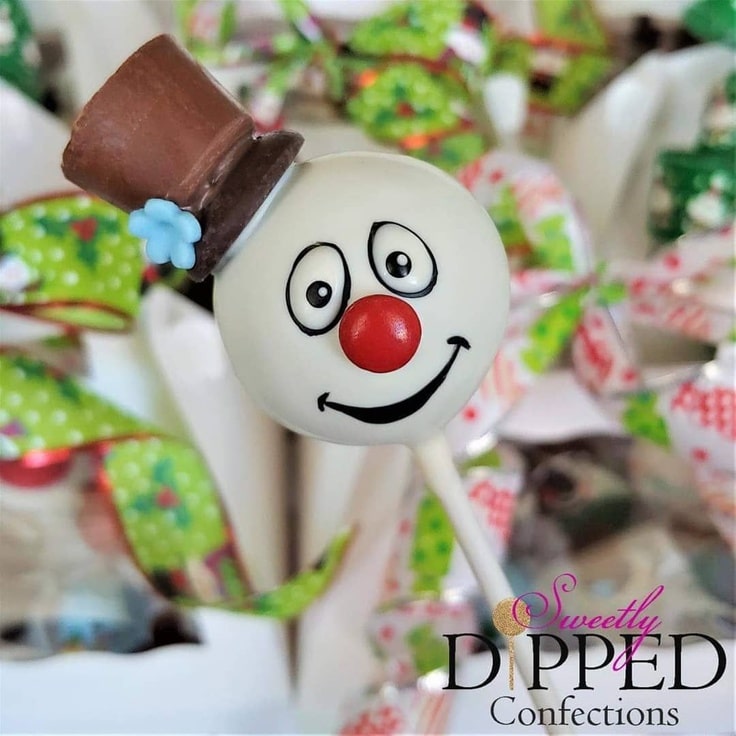 This is a close-up of a Frosty The Snowman Cake Pop. Frosty has a red nose and is wearing a brown top hat.