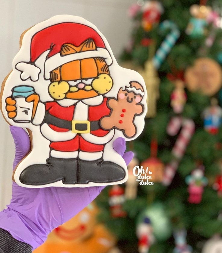 This cute cookie has Garfield dressed a Santa Claus and eating a gingerbread cookie.