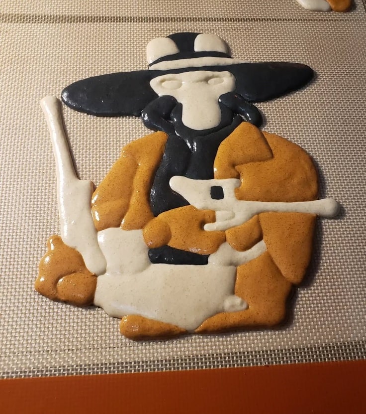 A photograph of the macaron before it had been painted. It is black, white and brown.