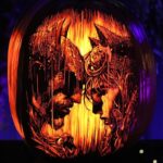 This pumpkin carving shows the faces of Batman and Catwoman about to kiss in the rain.